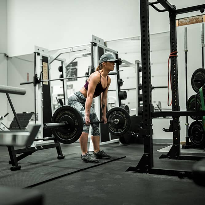 Image of a woman performing a deadlift at the gym