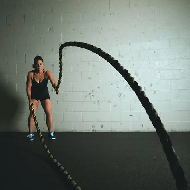 Image of a woman doing battle rope exercises at the gym