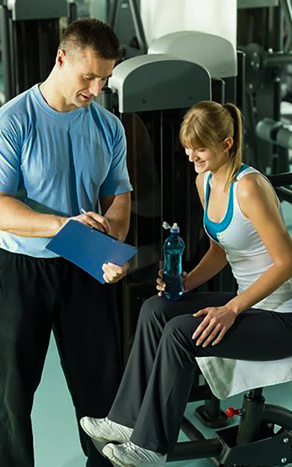 a woman and her trainer looking at her progress in the paper